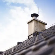 Komin na dachu z widocznym wkładem. Zastanawiasz się, ile kosztuje wkład kominowy do pieca gazowego?
