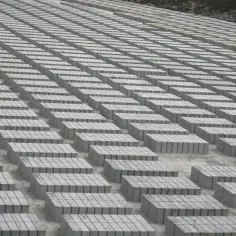 Ogromne pole betonowych bloczków ułożonych w równe rzędy. Trudno oszacować, ile bloczków betonowych na palecie, ale jest ich tysiące.