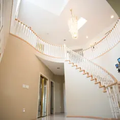 Elegancka osłona ściany przy schodach, z ozdobnym drzewem z rodzinnych zdjęć i kryształowym żyrandolem.
