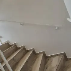 Nowoczesne balustrady wewnętrzne z białymi poręczami i drewnianymi stopniami tworzą elegancką przestrzeń.