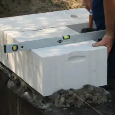 Użycie poziomicy i sznurka to kluczowe zasady murowania ścian z betonu komórkowego. Precyzyjne układanie bloczków zapewnia trwałość konstrukcji.