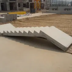 Na placu budowy leżą schody betonowe prefabrykowane, gotowe do montażu.