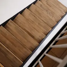 Drewniane stopnie schodów z czarną, metalową ramą i białymi balustradami.