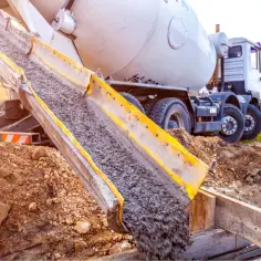 Betoniarka wylewa beton do szalunku. Pytanie brzmi, w jakich temperaturach można murować, aby zapewnić trwałość konstrukcji.