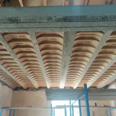 Widok od dołu na betonowy strop belkowo-pustakowy, gdzie widać żebra i pustaki ceramiczne. To właśnie co to strop.