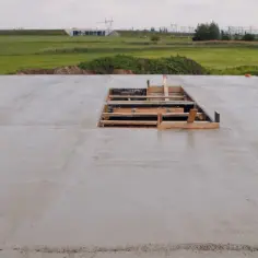 Świeżo wylany strop betonowy, widoczny otwór z szalunkiem. Pytanie, jak długo podlewać strop, jest kluczowe dla jego wytrzymałości.