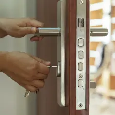 Dłonie wkładają klucz do zamka w drzwiach antywłamaniowych. Zapewniają bezpieczeństwo i spokój.