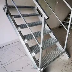 Solidne schody metalowe do piwnicy, wykonane z kraty pomostowej, zapewniają bezpieczne zejście.