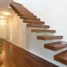 Nowoczesne, drewniane schody wychodzące ze ściany, tworzące lekki i minimalistyczny design.