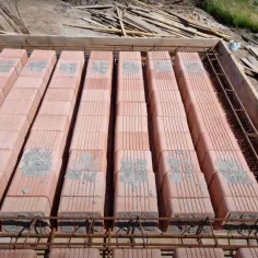 Widok z góry na strop ackermana przekrój: rzędy pustaków ceramicznych ułożone na zbrojeniu, gotowe do zalania betonem.