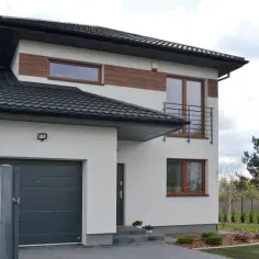 Nowoczesny dom bliźniak z garażem i drewnianymi elementami elewacji.