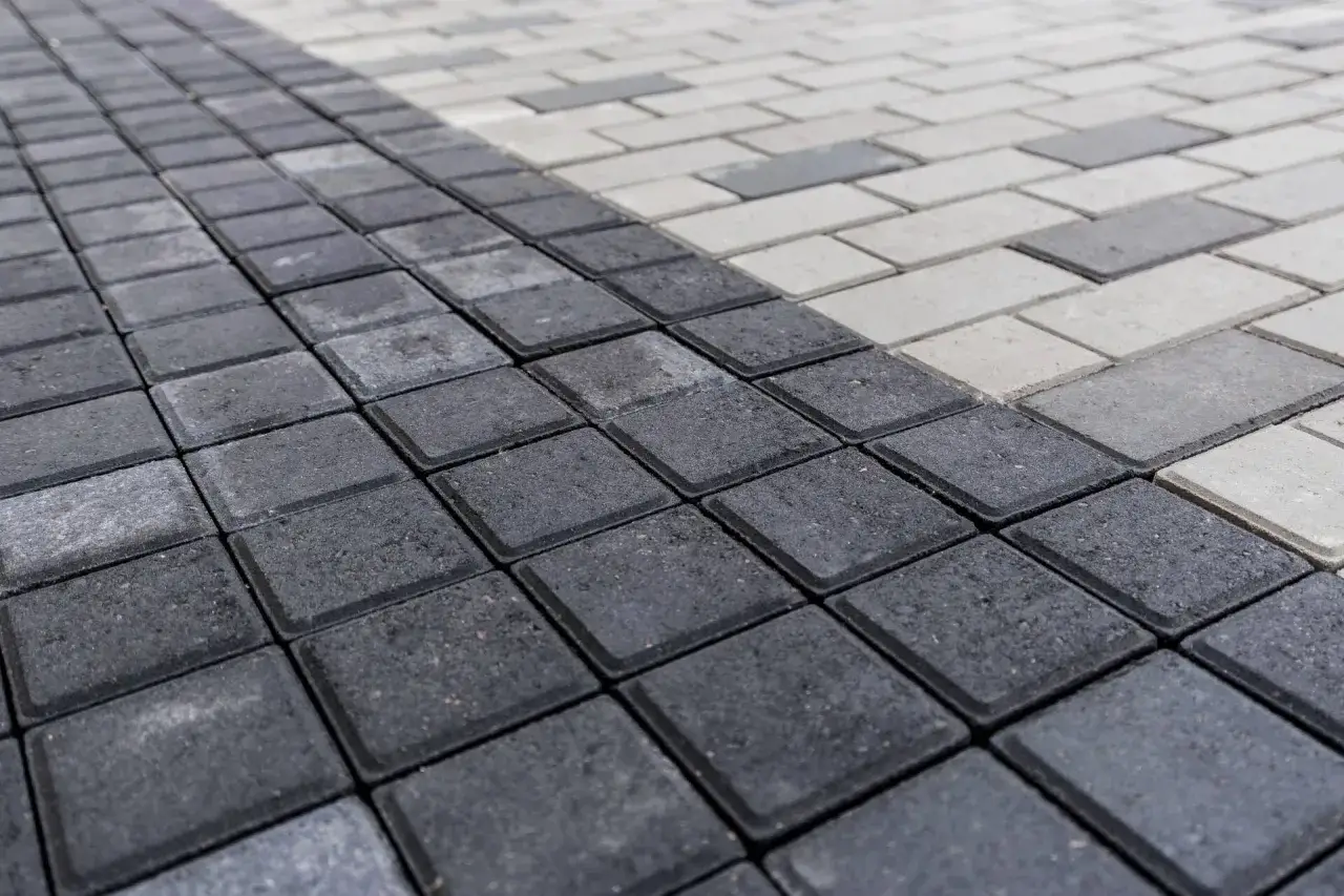 Szara i jasna kostka brukowa ułożona w geometryczny wzór. Zastanawiasz się, ile kosztuje położenie kostki brukowej?