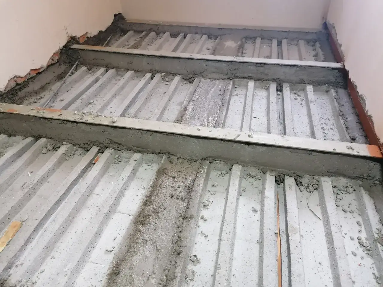 Strop na belkach stalowych w trakcie budowy. Betonowe elementy tworzą żłobienia, gotowe na dalsze prace.