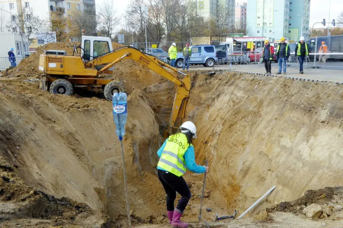 Prace ziemne koparką i geologiem w wykopie. Zastanawiasz się, ile kosztuje wybudowanie stacji benzynowej?