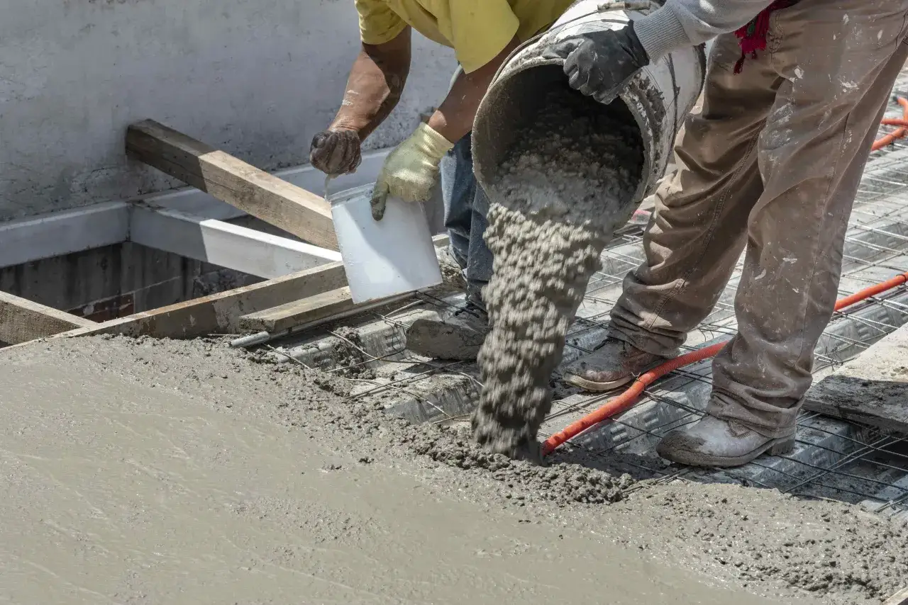 Pracownicy wylewają beton na zbrojenie. Po jakim czasie można murować na fundamencie? Czekamy na związanie betonu.