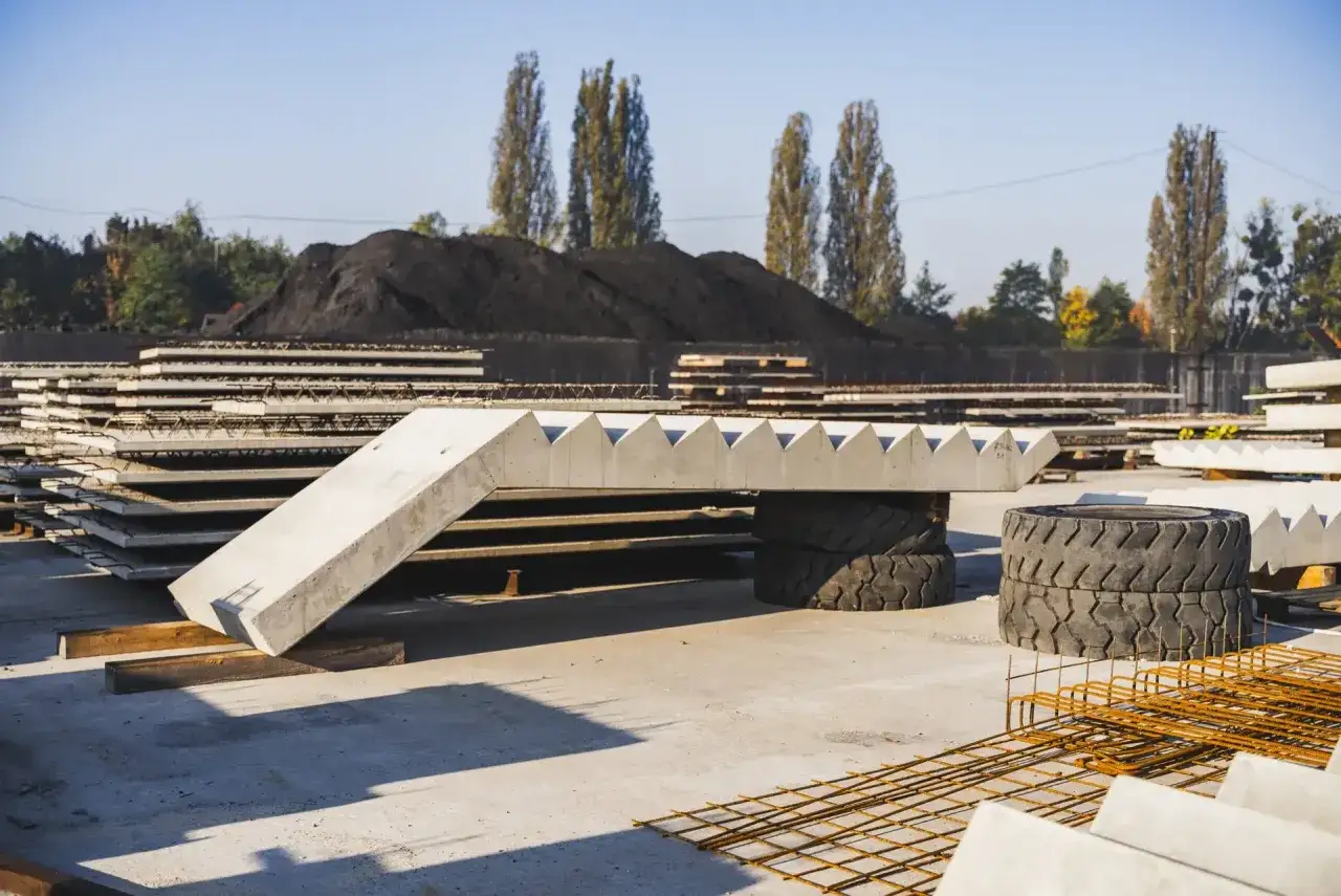 Gotowe schody betonowe zewnętrzne czekają na montaż. Stos gotowych elementów betonowych na placu budowy.