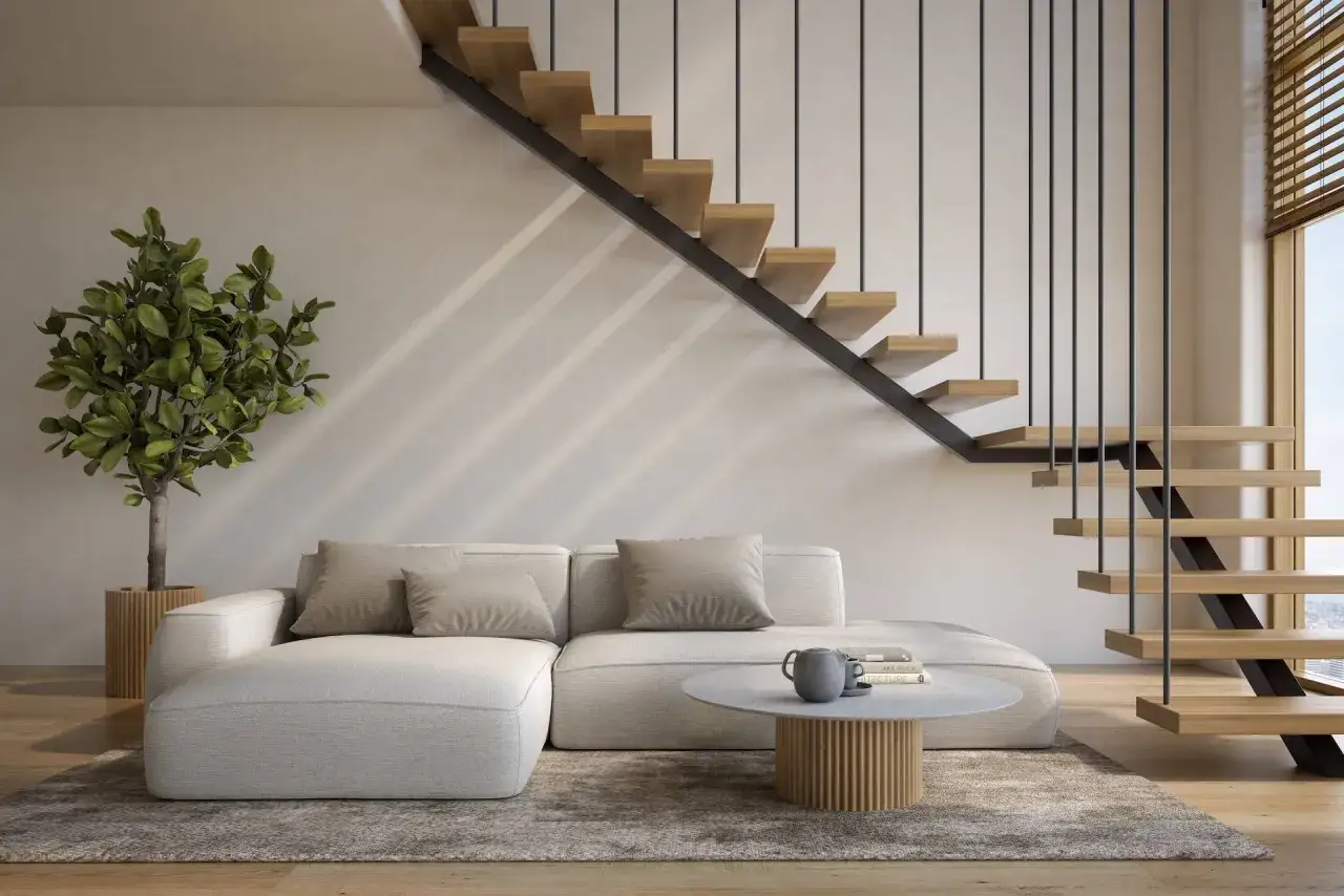 Nowoczesne, szare schody drewniane z metalową balustradą w minimalistycznym salonie. Obok wygodna kanapa i roślina.