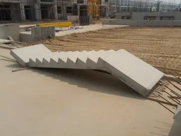 Na placu budowy leżą schody betonowe prefabrykowane, gotowe do montażu.